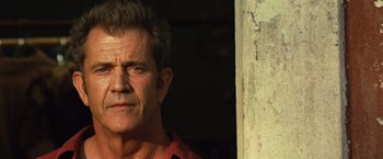 Movie still from “Get the Gringo” (2012), directed by Adrian Grunberg – A person wearing a red shirt near a wall; Close Up shot, Low angle