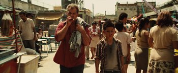 Movie still from “Get the Gringo” (2012), directed by Adrian Grunberg – A man and a boy walking down a street; Medium shot, Over the shoulder angle