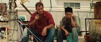 Movie still from “Get the Gringo” (2012), directed by Adrian Grunberg – A man and a boy sitting next to each other on the ground; Medium shot, Low angle