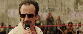 Movie still from “Get the Gringo” (2012), directed by Adrian Grunberg – A man with a beard and mustache is holding a microphone; Close Up shot, Low angle