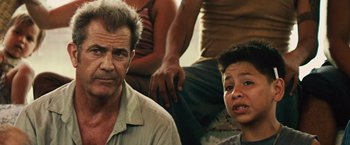 Movie still from “Get the Gringo” (2012), directed by Adrian Grunberg – A man and a woman sitting next to each other in front of other people; Close Up shot, Over the shoulder angle