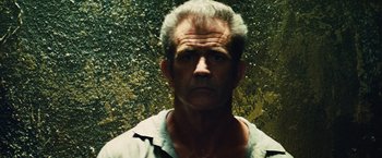 Movie still from “Get the Gringo” (2012), directed by Adrian Grunberg – An older man with a gray beard is looking at the camera; Close Up shot, Low angle