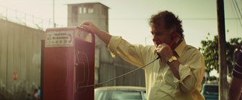 Movie still from “Get the Gringo” (2012), directed by Adrian Grunberg – A man talking on a payphone on the side of the road; Medium shot, Low angle
