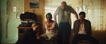 Movie still from “Get the Gringo” (2012), directed by Adrian Grunberg – A man with blood all over his face is sitting on a chair; Medium shot, Low angle