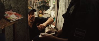 Movie still from “Get the Gringo” (2012), directed by Adrian Grunberg – A man in a police uniform sitting next to another man; Medium shot, Over the shoulder angle