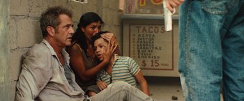 Movie still from “Get the Gringo” (2012), directed by Adrian Grunberg – A woman sitting next to a man in front of a sign; Medium shot, High angle