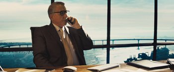 Movie still from “Get the Gringo” (2012), directed by Adrian Grunberg – An older man sitting at a table talking on a cell phone; Medium shot, Over the shoulder angle