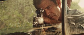 Movie still from “Get the Gringo” (2012), directed by Adrian Grunberg – A man is holding a rifle and looking through the scope; Close Up shot, High angle