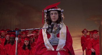Movie still from “Ghost World” (2001), directed by Terry Zwigoff – A girl in a graduation cap and gown with a microphone in front of a group of people; Medium shot, Low angle