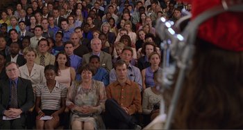 Movie still from “Ghost World” (2001), directed by Terry Zwigoff – A group of people sitting in front of a microphone; Wide shot, High angle