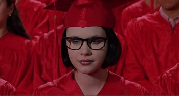 Movie still from “Ghost World” (2001), directed by Terry Zwigoff – A woman wearing a red cap and gown and glasses; Close Up shot, Low angle