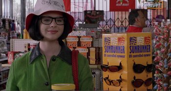 Movie still from “Ghost World” (2001), directed by Terry Zwigoff – A woman wearing a hat and sunglasses in a store; Close Up shot, Over the shoulder angle