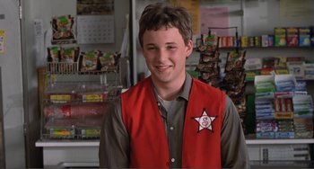 Movie still from “Ghost World” (2001), directed by Terry Zwigoff – A young man in a red vest smiling for the camera; Medium shot, Over the shoulder angle