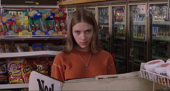 Movie still from “Ghost World” (2001), directed by Terry Zwigoff – A young girl in an orange shirt is looking at the camera; Medium shot, Over the shoulder angle