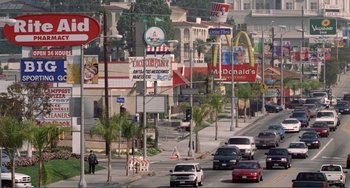 Movie still from “Ghost World” (2001), directed by Terry Zwigoff – A busy street with a lot of cars on the side of the road; Extreme Wide shot, High angle