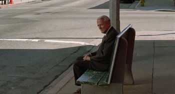 Movie still from “Ghost World” (2001), directed by Terry Zwigoff – An older man in a suit sitting on top of a bench; Wide shot, High angle