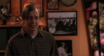 Movie still from “Ghost World” (2001), directed by Terry Zwigoff – A man standing in front of a wall with a picture on the wall; Close Up shot, High angle