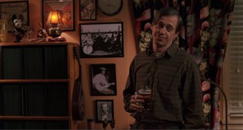 Movie still from “Ghost World” (2001), directed by Terry Zwigoff – A man holding a glass of beer in his hand; Medium shot, High angle