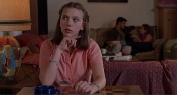 Movie still from “Ghost World” (2001), directed by Terry Zwigoff – A young woman sitting at a table in a living room; Medium shot, Over the shoulder angle