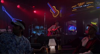 Movie still from “Ghost World” (2001), directed by Terry Zwigoff – A man sitting at a table playing a guitar; Wide shot, Over the shoulder angle