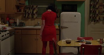 A woman in a red dress standing in front of a refrigerator