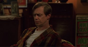 Movie still from “Ghost World” (2001), directed by Terry Zwigoff – A man sitting in a chair wearing a plaid shirt; Medium shot, High angle