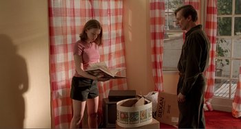 Movie still from “Ghost World” (2001), directed by Terry Zwigoff – A girl is reading a book while another girl looks on; Medium shot, Low angle