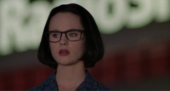 Movie still from “Ghost World” (2001), directed by Terry Zwigoff – A woman with short black hair wearing glasses and a plaid shirt; Close Up shot, Over the shoulder angle