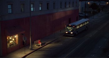 Movie still from “Ghost World” (2001), directed by Terry Zwigoff – A man sitting on a park bench next to a bus; Extreme Wide shot, High angle