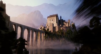 An old castle with a bridge in front of it and mountains in the background