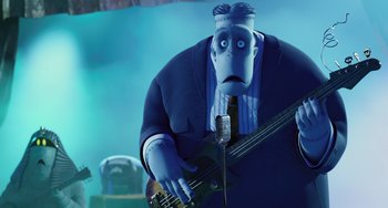 Movie still from “Hotel Transylvania” (2012), directed by Genndy Tartakovsky – A man in a suit and tie playing a guitar; Medium shot, Low angle