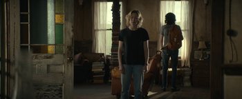 Movie still from “Ghostbusters: Afterlife” (2021), directed by Jason Reitman – A woman standing in a living room with luggage; Wide shot, Low angle