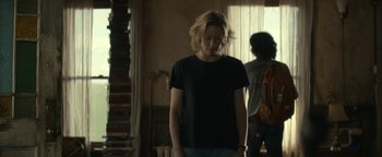 Movie still from “Ghostbusters: Afterlife” (2021), directed by Jason Reitman – A woman standing in front of a window in a room; Medium shot, Over the shoulder angle