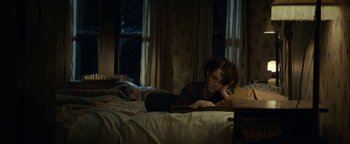 Movie still from “Ghostbusters: Afterlife” (2021), directed by Jason Reitman – A woman is reading a book in a dark room; Medium shot, High angle