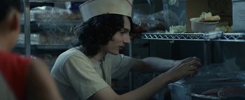 Movie still from “Ghostbusters: Afterlife” (2021), directed by Jason Reitman – A young man wearing a hat in a kitchen; Medium shot, Low angle