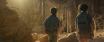 Movie still from “Ghostbusters: Afterlife” (2021), directed by Jason Reitman – A young boy with a backpack walking through a cave; Wide shot, Low angle