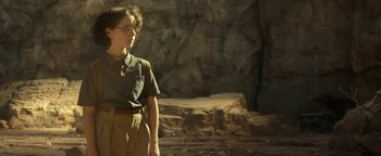 Movie still from “Ghostbusters: Afterlife” (2021), directed by Jason Reitman – A person standing in front of a stone wall; Medium shot, Low angle