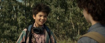 Movie still from “Ghostbusters: Afterlife” (2021), directed by Jason Reitman – A young man wearing a backpack and headphones smiles; Close Up shot, Over the shoulder angle