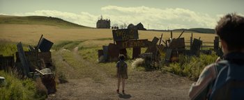 Movie still from “Ghostbusters: Afterlife” (2021), directed by Jason Reitman – A person standing on a dirt road near a field; Extreme Wide shot, High angle