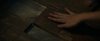 Movie still from “Ghostbusters: Afterlife” (2021), directed by Jason Reitman – A person's hand on top of a piece of wood on the floor; Extreme Close Up shot, Overhead angle