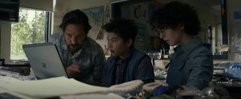 Movie still from “Ghostbusters: Afterlife” (2021), directed by Jason Reitman – A man and a boy and an older man looking at a piece of paper; Medium shot, Over the shoulder angle