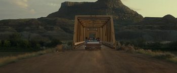 Movie still from “Ghostbusters: Afterlife” (2021), directed by Jason Reitman – A car is driving on a dirt road under a bridge; Extreme Wide shot, High angle
