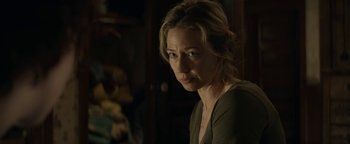 Movie still from “Ghostbusters: Afterlife” (2021), directed by Jason Reitman – A woman is looking at the camera in a dark room; Close Up shot, Over the shoulder angle