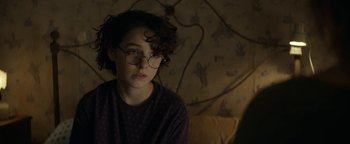 Movie still from “Ghostbusters: Afterlife” (2021), directed by Jason Reitman – A young woman wearing glasses sitting on a couch; Close Up shot, Over the shoulder angle