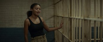 Movie still from “Ghostbusters: Afterlife” (2021), directed by Jason Reitman – A woman standing next to a wall in a jail cell; Medium shot, Over the shoulder angle