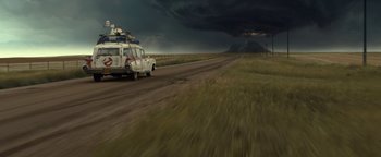 Movie still from “Ghostbusters: Afterlife” (2021), directed by Jason Reitman – A car driving down a road under a dark sky; Extreme Wide shot, Low angle