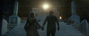 Movie still from “Ghostbusters: Afterlife” (2021), directed by Jason Reitman – A man and a woman holding hands while standing in front of steps; Wide shot, Low angle