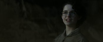 Movie still from “Ghostbusters: Afterlife” (2021), directed by Jason Reitman – A young woman wearing glasses and smiling for the camera; Close Up shot, Low angle