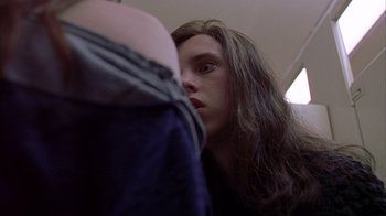 A woman with long brown hair looking into a mirror