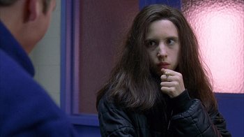 A woman with long dark hair is sitting in a room
